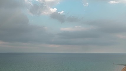 Wall Mural - A zoom out aerial timelapse of fluffy white clouds filling a blue sky and then disappearing over Lake Michigan on the north side of Chicago and Foster Beach during sunset.