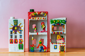 A toy house made of a box from juice and a plasticine family living in it. Creative paper bag ideas. Recycle crafts.