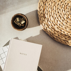 Wall Mural - Flatlay notebooks, clips in wooden bowl, straw stand on beige concrete background. Office desk workspace. Business, work blank template. Flat lay, top view.