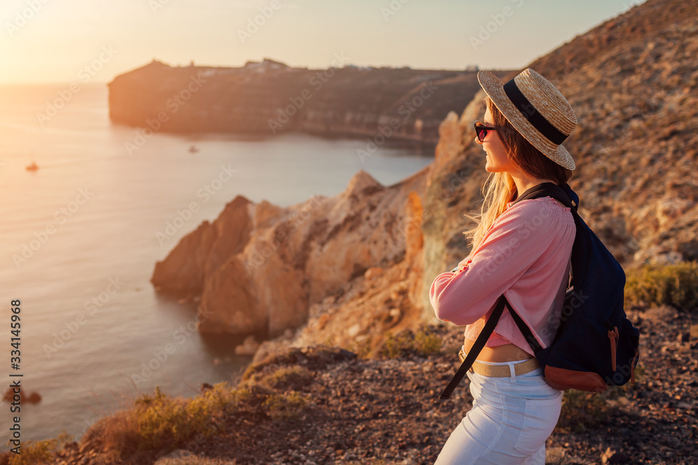 Traveler hiking by White beach on Aegean sea Santorini island, Greece enjoying landscape. Woman backpacker on vacation - obrazy, fototapety, plakaty 