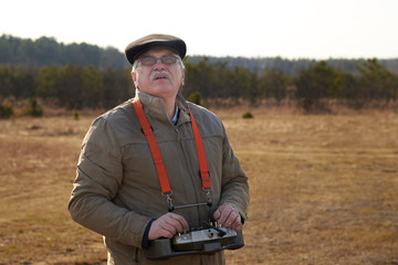 Wall Mural - An elderly man controls a radio-controlled aircraft using the remote control.