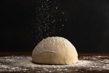 Pastry Chef Sprinkles Flour On Fresh Raw Dough For Bread Or Pizza On A Dark Background.