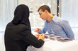 © ALEXEY - A man at an Islamic country information desk. Caucasian man communicates with a Muslim woman in the information center.