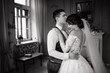 Happy groom kisses the bride on the forehead, hugging her waist in a vintage interior. Beautiful elegant couple of newlyweds in love. Wedding concept. Happy newlywed couple.