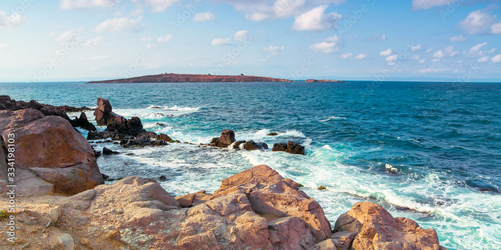 seascape with rocks and cliffs. beautiful scenery in the afternoon light. island in the distance. fluffy clouds on the evening sky. st. Ivan and st. Peter island of bulgaria in the distance - obrazy, fototapety, plakaty 