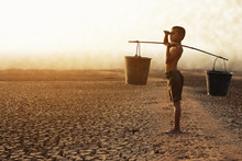 The Boy Sat On A Parched Ground Due To Water Shortage Due To Global Warming. Global Warming And Climate Change Concept