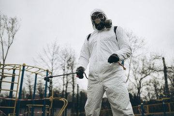 Wall Mural - Cleaning and Disinfection on the playground in the sity complex amid the coronavirus epidemic Teams for disinfection efforts Infection prevention and control of epidemic Protective suit and mask