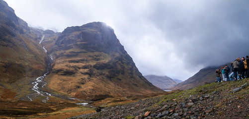 Amazing yellow and green mountain landscape with a small river coming down and a group of people taking pictures