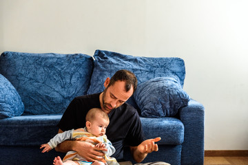 Wall Mural - Funny baby sitting on his father's legs resting relaxed.