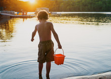 Young Boy Standing In A Lake Holding A Bucket, Bedford, Halifax, Nova Scotia, Canada