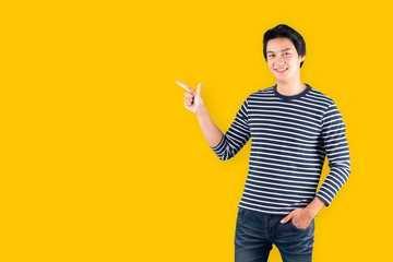 Young handsome Asian man / happy guy pointing to above copy space isolated over blue background, studio shot