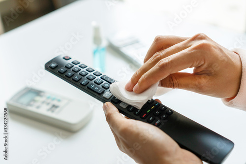 Fotografía Woman hand cleaning TV remote controller with disinfectant wet wipe and alcohol in living room at home