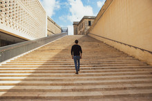 A Young Man Climbing Up Along Large Endless Stair Alone