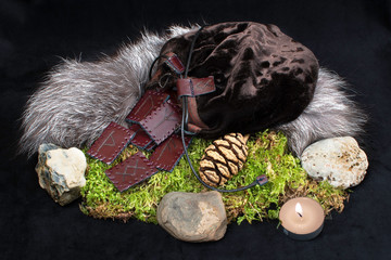 Wall Mural - A set of 24 brown leather Norse runes in a bag on a background of fur, moss, stones and a candle.