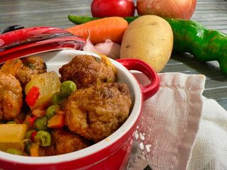 Canvas Print - Meatballs with potatoes and peas in a red casserole, carrot, tomato and potato