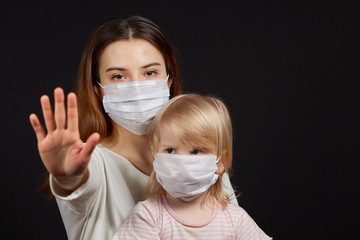 a girl in a mask shows a stop gesture fearing for the health of people