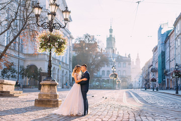 Wall Mural - beautiful newlyweds hugging each other in the old town square ne