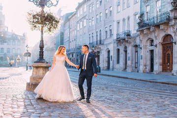 Wall Mural - the bride and groom hold hands and look at each other. walk thro