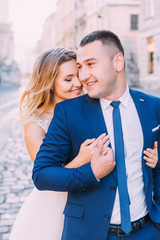 Wall Mural - the bride hugs the groom from the back side and they closed thei