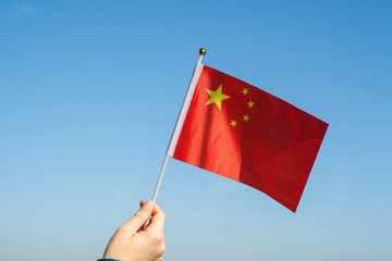 Canvas Print - Woman hand with Chinese swaying flag on the blue sky. China.Concept