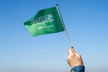 Wall Mural - Muslim woman with Saudi Arabia flag on the blue sky. Concept