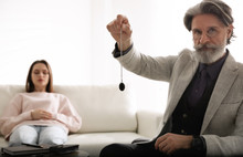 Psychotherapist Using Pendulum During Hypnotherapy   Session In Office