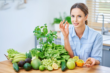 Healthy adult woman with green food in the kitchen