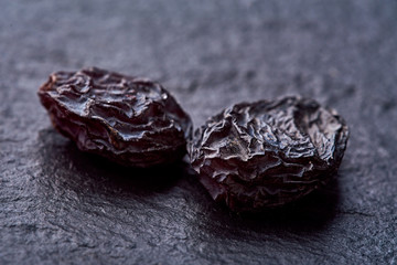 two raisins lies on a black rough surface. macro shot