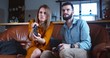© vadim_key - Young happy Caucasian married couple play console videogame with joysticks having big fun together at home slow motion.