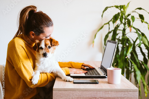 Cuadros en Lienzo young woman working on laptop at home,cute small dog besides