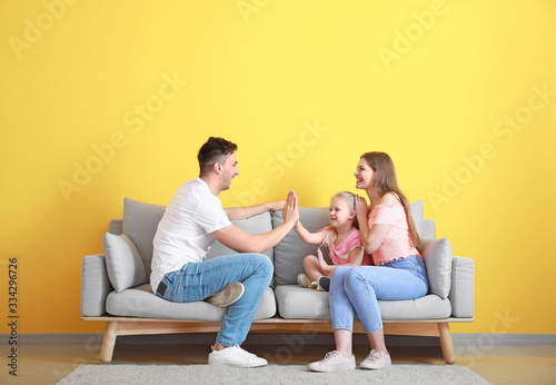 Happy young family playing while sitting on sofa near color wall Tableau sur Toile