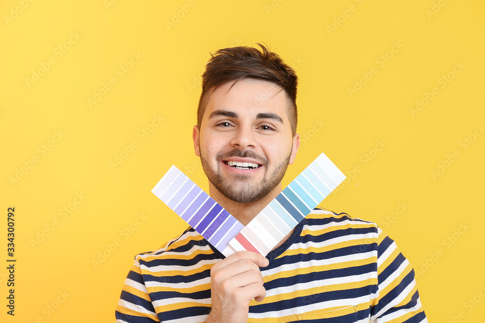 Young man with paint palette on color background