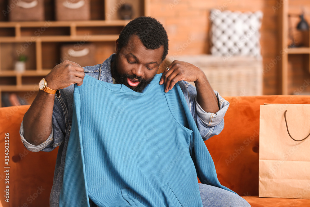 African-American man with received new clothes at home