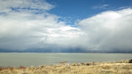 Wall Mural - Low clouds moving over Utah Lake as it rains while the sun is shining.