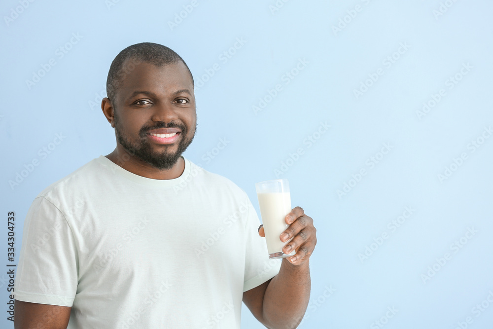 African-American man with milk on color background