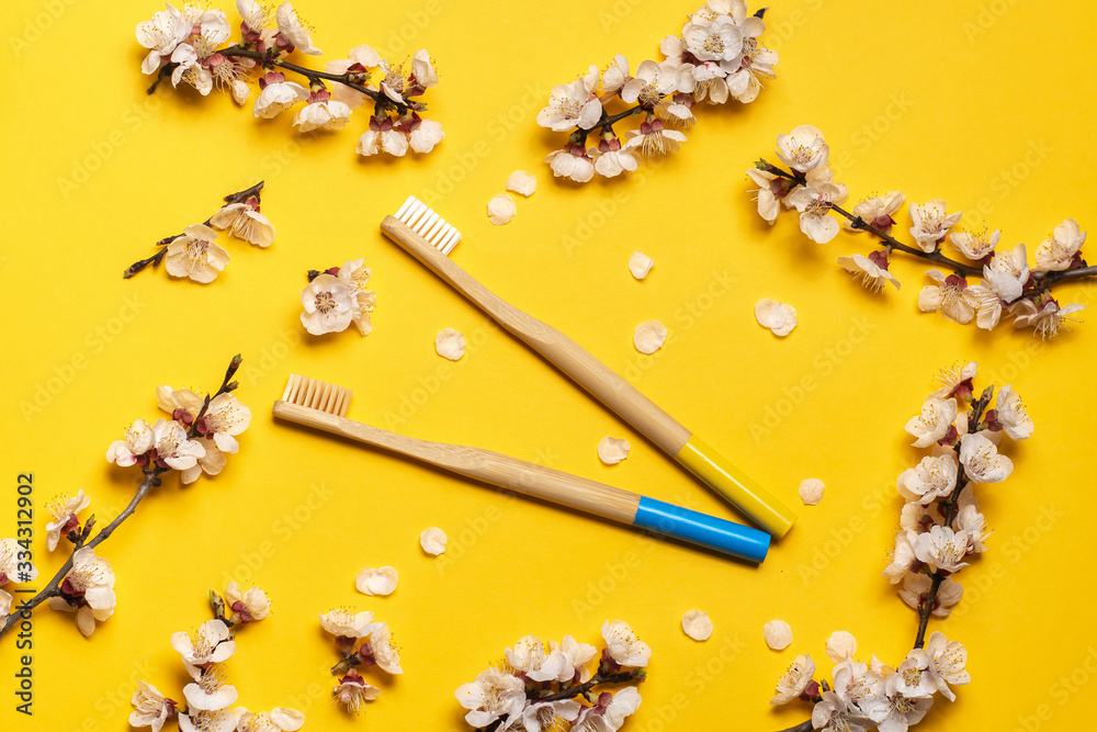 blue and yellow bamboo toothbrushes on a yellow background in an oval ...