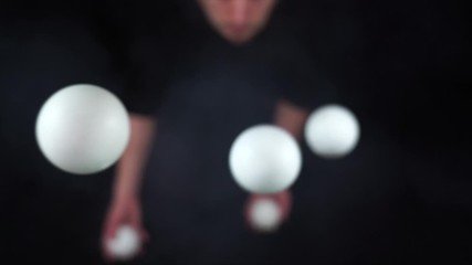 Wall Mural - Circus artist wearing black juggling with white balls in slow motion