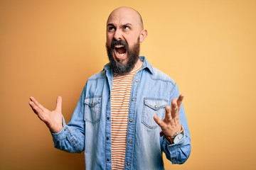 Poster - Handsome bald man with beard wearing casual denim jacket and striped t-shirt crazy and mad shouting and yelling with aggressive expression and arms raised. Frustration concept.