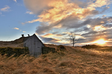 Rural and traditional turfy shelter in Iceland, Europe. Dramatic sunset during wintertime in Viking`s land.