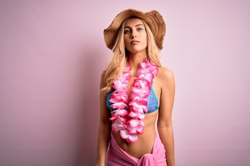 Sticker - Young beautiful blonde woman on vacation wearing bikini and hat with hawaiian lei flowers Relaxed with serious expression on face. Simple and natural looking at the camera.