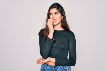 Poster - Young beautiful brunette woman wearing casual sweater and jeans standing over isolated background looking stressed and nervous with hands on mouth biting nails. Anxiety problem.