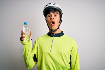 Poster - Young handsome cyclist man wearing security bike helmet drinking bottle of water scared in shock with a surprise face, afraid and excited with fear expression