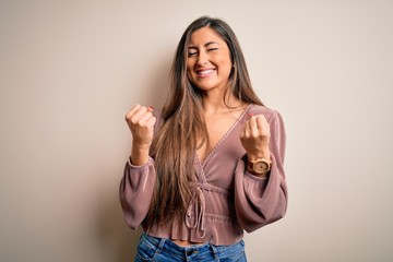 Young beautiful brunette elegant woman with long hair standing over isolated background excited for success with arms raised and eyes closed celebrating victory smiling. Winner concept.