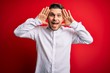 © Krakenimages.com - Young business man with blue eyes wearing elegant shirt standing over red isolated background Smiling cheerful playing peek a boo with hands showing face. Surprised and exited