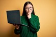 Young asian business woman wearing glasses and working using computer laptop looking confident at the camera smiling with crossed arms and hand raised on chin. Thinking positive.