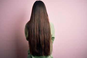 Wall Mural - Young beautiful asian woman wearing green winter sweater over pink solated background standing backwards looking away with crossed arms