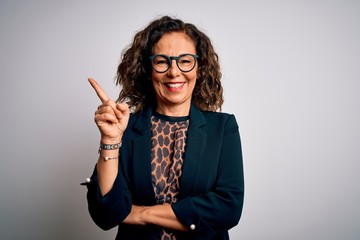 Middle age brunette business woman wearing glasses standing over isolated white background with a big smile on face, pointing with hand and finger to the side looking at the camera.