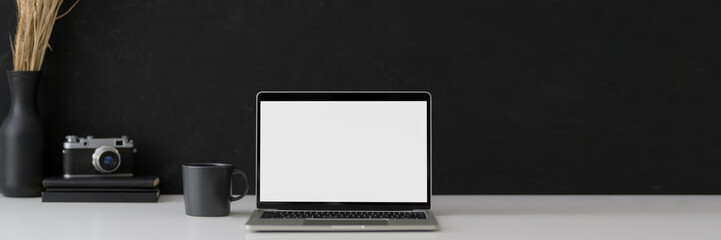 Cropped shot of black and white workspace with mock-up laptop, camera, supplies and copy space