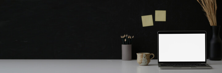 Cropped shot of black and white concept workspace with copy space, mock-up laptop, stationery and decorations