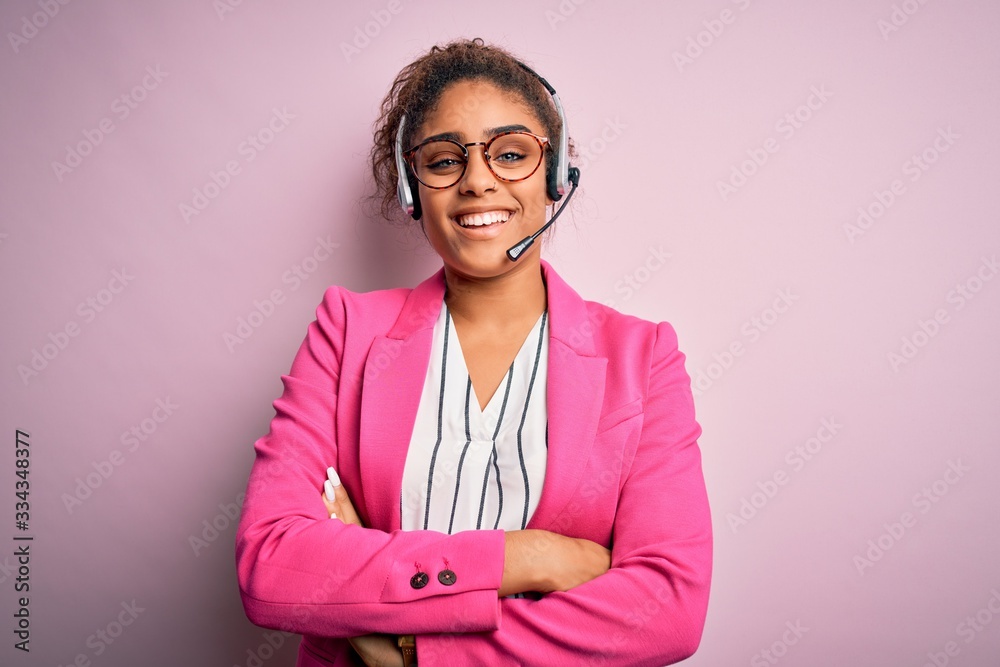 Young african american call center agent girl wearing glasses working using headset happy face smiling with crossed arms looking at the camera. Positive person. - obrazy, fototapety, plakaty 